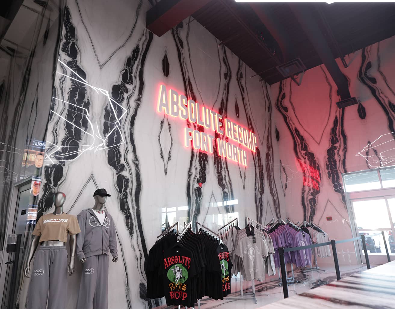Merchandise shop inside Absolute Recomp Fort Worth with branded apparel displays and wall signage