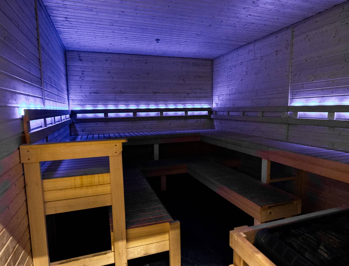 Sauna inside Absolute Recomp Lewisville with wood interior and blue ambient lighting