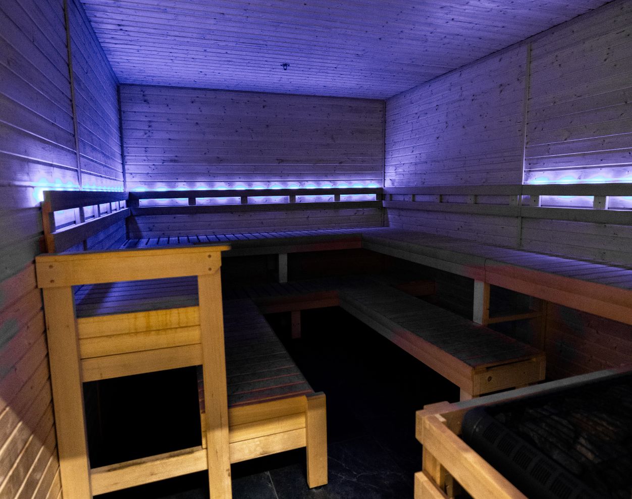 Wood sauna recovery room with bench seating and accent lighting at Absolute Recomp Gyms Fort Worth