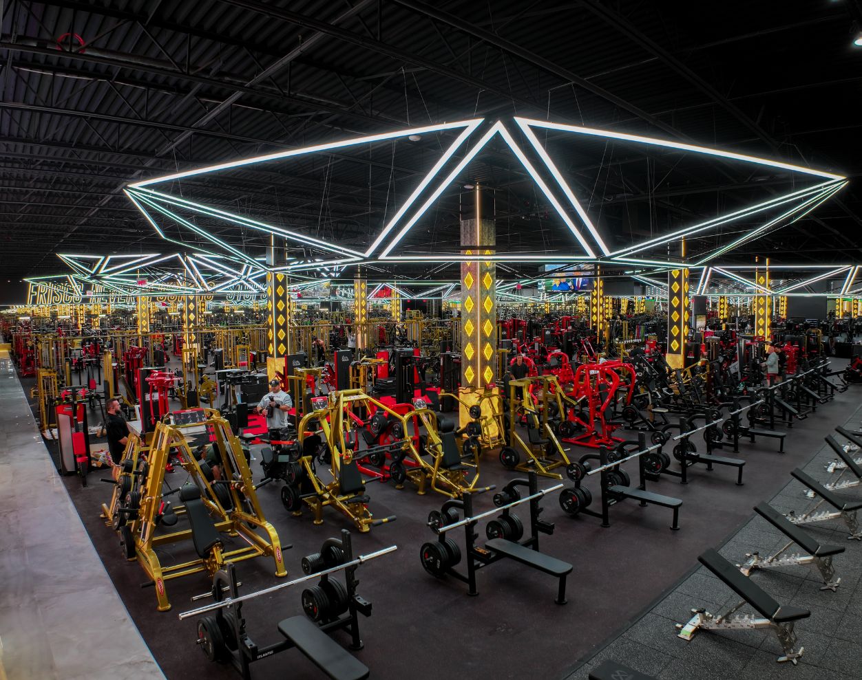 Expansive strength training floor with free weights, benches, and plate-loaded equipment at Absolute Recomp Gyms Frisco