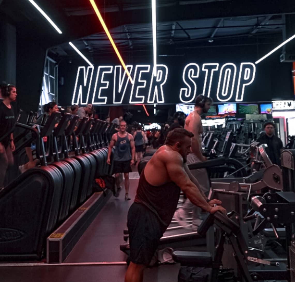 Cardio training area inside Absolute Recomp with stair climbers and Never Stop wall sign