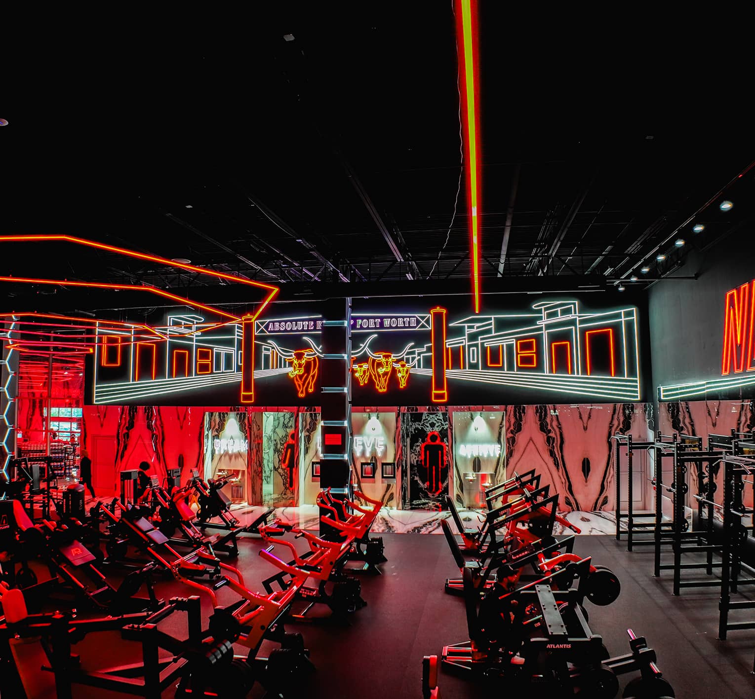 Absolute Recomp gym interior with strength equipment and neon lighting